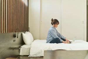 高松FAV HOTEL TAKAMATSU的坐在床上的女士,手提电脑