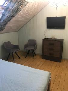 布克维Chalet Blanc的一间卧室配有一张床、两把椅子和电视