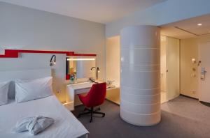 维尔纽斯维尔纽斯假日酒店的酒店客房配有一张床、一张红色椅子和一张书桌