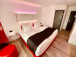布雷滕DORMERO Hotel Bretten的卧室配有红色色调的大型白色床