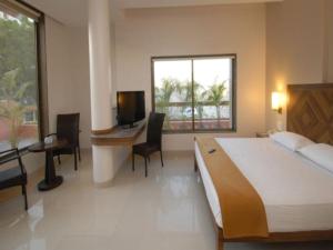 舍地Sai Palace Budget Hotel的一间卧室配有一张床、一张书桌和一台电视