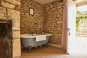 希普顿－安德威奇伍德The Lamb Inn的石墙客房内的浴缸