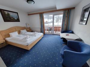基茨比厄尔附近奥拉赫Ferienhotel Alpenhof的配有一张床和一把椅子的酒店客房