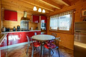 LathuilleLe Chalet Bonheur的厨房配有红色橱柜和桌椅