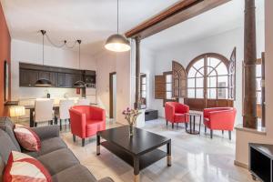 格拉纳达BnS Dauro Suites的开放式客厅以及带红色椅子和桌子的厨房