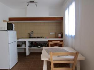 埃斯卡洛VIVIENDAS TURISTICAS CAN MARIANO BARBER - ES CALÓ - FORMENTERA的一间带桌子和白色冰箱的小厨房