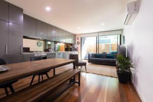 墨尔本Experience Port Melbourne的厨房以及带木桌和椅子的客厅。