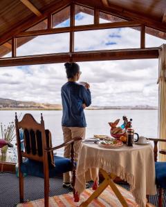 普诺Luz del Titicaca Lodge的坐在桌子上从窗户望出去的女人