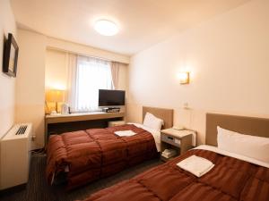 松本Hotel Iidaya的酒店客房设有两张床和电视。