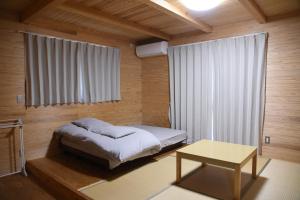 南阿苏村瓦卡旅馆的一间卧室配有一张床、一张桌子和一个窗户。