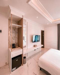 JomblangKala Hotel Semarang的一间卧室配有一张床,墙上配有电视