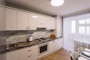 捷尔诺波尔Затишна квартира біля парку Центр міста的厨房配有白色橱柜和炉灶烤箱。