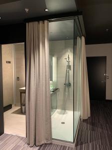 布兰维尔Grand Hotel TiMES Blainville-Mirabel的浴室设有玻璃淋浴间和淋浴帘