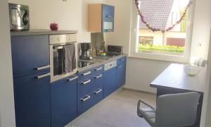 默讷塞--- SEEDOMIZIL --- moderne Ferienwohnung mit Terrasse的厨房配有蓝色橱柜、桌子和窗户。