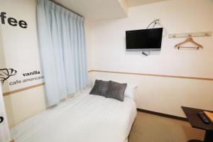 东京Hotel Yuyukan - Vacation STAY 10008v的卧室配有一张床,墙上配有电视。