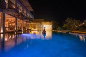 巴卡拉尔Hotel Makaabá Eco-Boutique的夜间坐在游泳池里的人