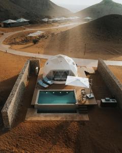 沙迦Moon Retreat by Sharjah Collection的沙漠中的室外游泳池,配有遮阳伞和椅子