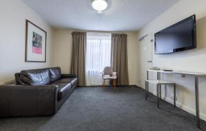 堪培拉福雷斯特公寓酒店的客厅配有真皮沙发和平面电视