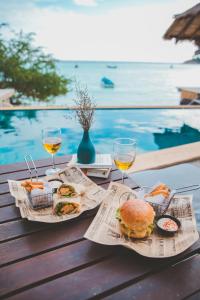 涛岛纽哈文潜水度假村的一张桌子,上面放着两杯葡萄酒和三明治及食物