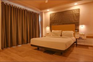 GauripurFabHotel Suncitel Dum Dum Airport的一间卧室配有一张大床和木制床头板