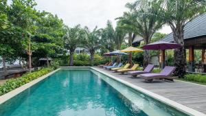 罗威那The Grand Villandra Resort的房屋旁的游泳池配有椅子和遮阳伞