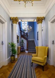 邓迪The Clarendon的走廊上设有柱子、黄色椅子和楼梯