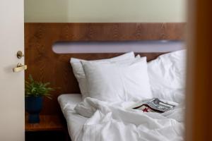 塔尔图Hotel Soho的一张带白色床单和枕头的床,上面有书
