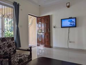 达波林Tangerine Stay - Friends & Family 4BHK Villa, Goa的客厅配有沙发和墙上的电视