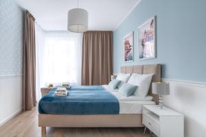格丁尼亚Symphony Modern Tower Aparthotel的一间卧室配有一张带蓝色毯子的大床