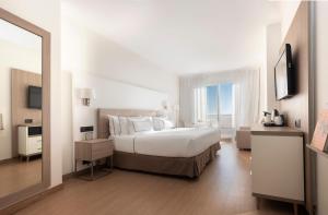 锡切斯锡切斯美利亚酒店的白色卧室设有一张大床和镜子