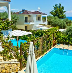 萨索斯Thassian Villas的一座带游泳池和遮阳伞的别墅