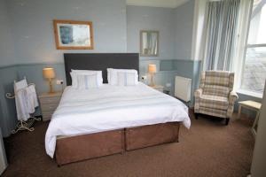 陶因Leahurst Bed and Breakfast的一间卧室配有一张大床和一把椅子