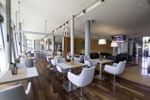 不来梅港Nordsee Hotel Fischereihafen的一间设有白色桌子和白色椅子的餐厅