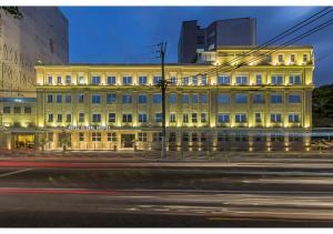 圣保罗Hotel Global Grupos的夜幕降临的城市街道上一座黄色的大建筑