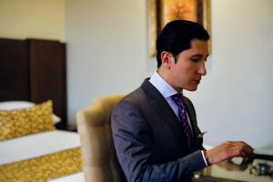 昆卡Hotel Patrimonio的穿着西装打领带的年轻人看着他的手表