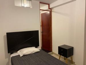 帕拉卡斯Hotel Munay的一间卧室配有一张床和一个黑色床头柜