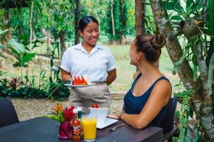 霍普金斯博卡维纳雨林度假村的坐在桌子旁的妇女,拿着一盘食物