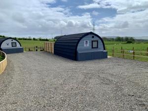 GalstonThistle Pod at Ayrshire Rural Retreats Farm Stay Hottub Sleeps 2的几个蓝色的储存棚在田野里