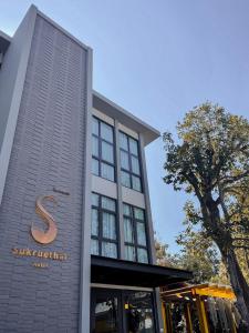 清迈Sukruethai Hotel Chiang Mai - โรงแรมสุขฤทัย เชียงใหม่的建筑的侧面有标志