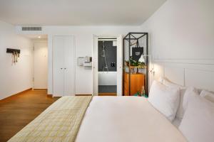 苏黎世马克加赛酒店的一间带白色大床的卧室和一间浴室