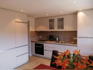 埃尔察赫Stockerhof的厨房配有白色橱柜和鲜花桌