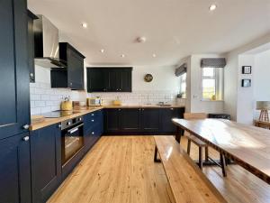 卡弗拉克Arrowan Common Farm Cottages的厨房配有蓝色橱柜和木桌