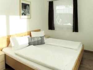 奇勒谷地拉姆绍Apartment Hanser - MHO754 by Interhome的一间卧室配有一张带白色床单的床和一扇窗户。