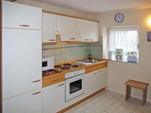 VerchenHoliday Home Am See II by Interhome的厨房配有白色橱柜和炉灶烤箱。