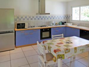 梅桑热Holiday Home Le Moïsan - MES120 by Interhome的厨房配有蓝色橱柜、桌子和微波炉