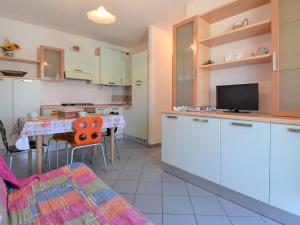 洛萨皮内塔Apartment Solmare-7 by Interhome的厨房配有白色橱柜和带电视的桌子。