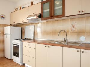 拉布Apartment Matius - RAB105 by Interhome的厨房配有白色橱柜、水槽和冰箱。