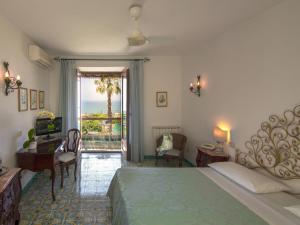 伊斯基亚Semiramis Hotel De Charme & Pools的一间卧室配有一张床、一张书桌和一个窗户。
