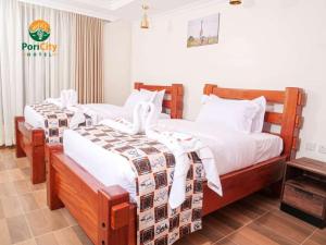 内罗毕Pori City Hotel的一间卧室配有两张带白色床单的床