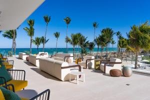 蓬塔卡纳Tropical Deluxe Princess - All Inclusive的海滩上带椅子和棕榈树的庭院